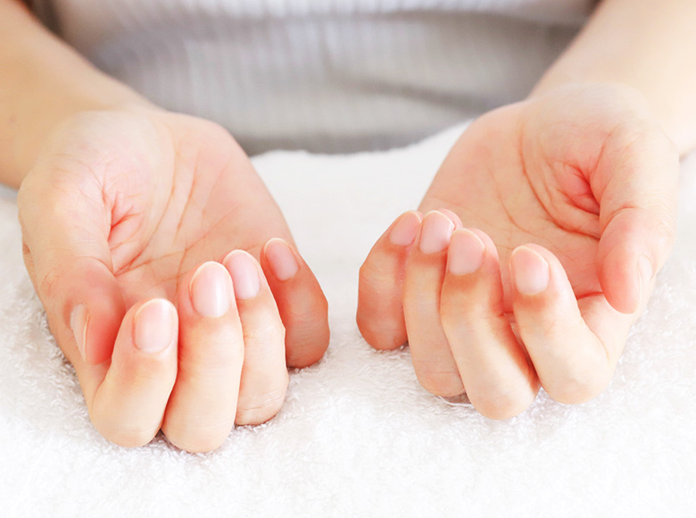 手のひらを上に向けて、手を前に置く女性